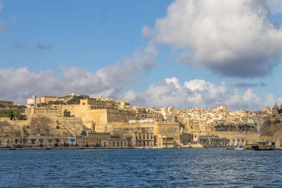 Buildings by sea against sky in city