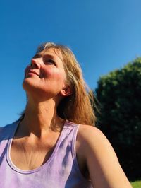 Low angle portrait of woman against blue sky