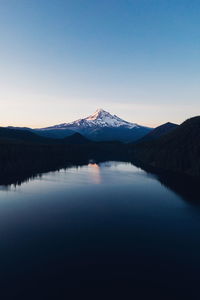 Scenic view of lake and snowcapped mountain against clear sky during sunset
