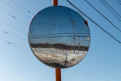 Low angle view of telephone pole against clear blue sky