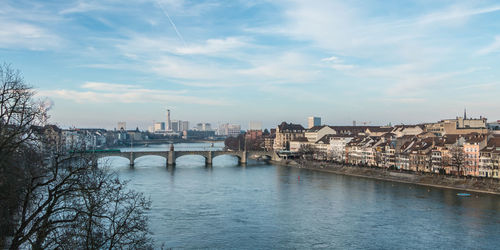 Bridge over river by buildings against sky in city