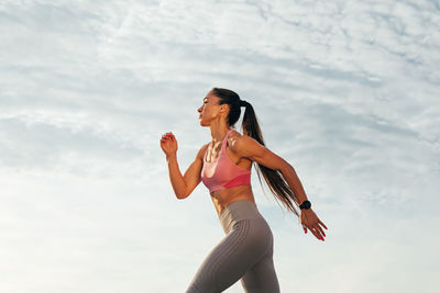 Portrait of young woman standing against sky