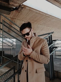 Young man smoking cigarette while standing on staircase