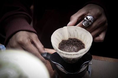 Cropped hands of person making coffee on table