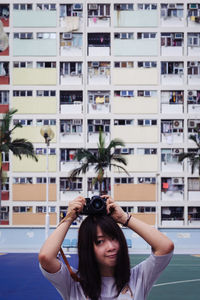 Woman with camera on head against building