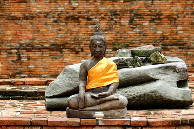 Buddha statue against brick wall