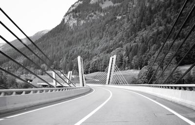 Vehicles on road by mountain against sky