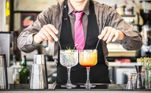 Midsection of bartender preparing drink at counter