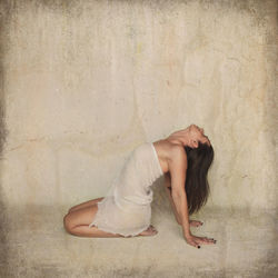 Side view of mature woman doing yoga against wall