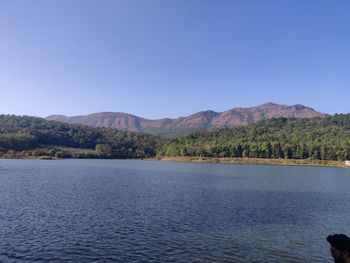 Scenic view of lake and mountains against clear blue sky