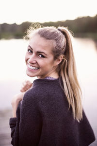 Portrait of happy young woman at lakeshore