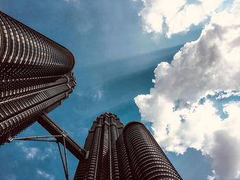 Low angle view of twin tower malaysia against cloudy sky