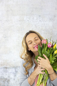 Woman holding flowers against wall