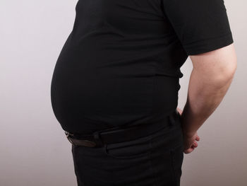 Midsection of woman wearing hat standing against white background