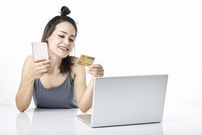 Smiling young woman using smart phone against white background