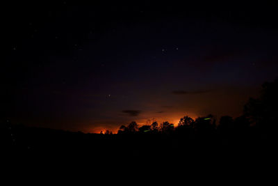 Silhouette trees against sky at night