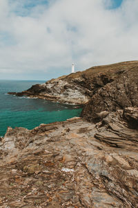 Scenic view of ocean coast and a lighthouse against sky 