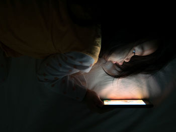 Midsection of woman holding mobile phone in bed