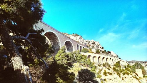 Low angle view of arch bridge against blue sky