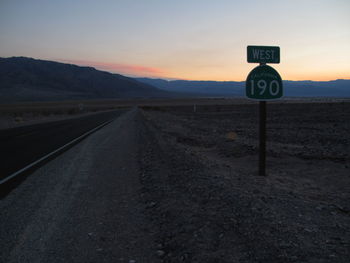 Road sign against sky during sunset