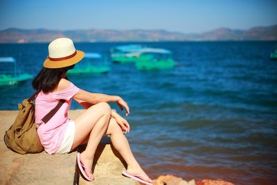 Woman sitting by sea