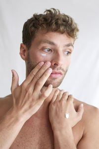 Portrait of shirtless young man over white background