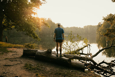 Rear view of man standing by trees against sky