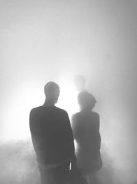 Rear view of man and woman standing in fog
