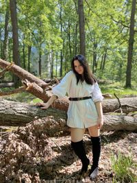 Full length of young woman standing in forest