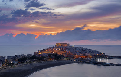 Scenic view of sea and buildings against sky during sunset