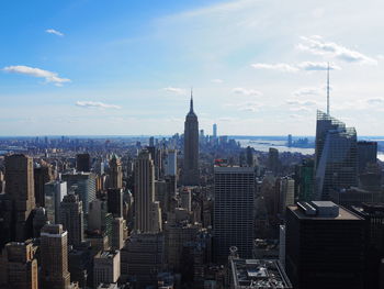 Aerial view of buildings in city against cloudy sky