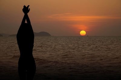 Rear view of woman standing at sunset