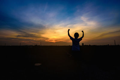 Rear view of silhouette man standing on field against sky during sunset