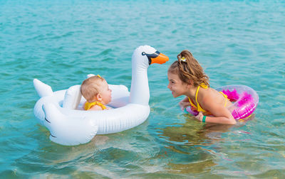 Smiling girl looking at sister in swimming pool