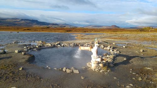 Scenic view of stream by landscape against sky