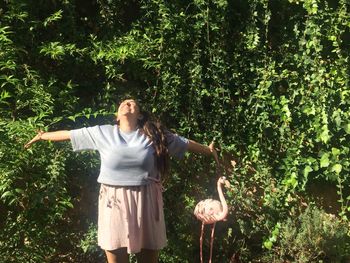 Woman standing by tree against plants