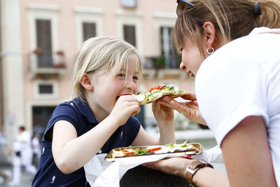 Italy, mother and little daughter eating pizza together