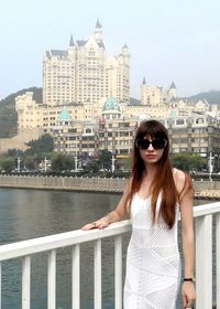 Portrait of a young woman standing on railing