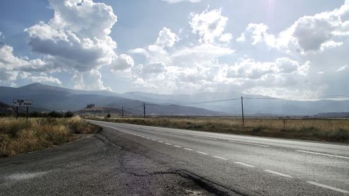 Empty road by mountains against sky