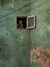 Portrait of woman by window on wall