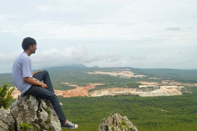 Man sitting on rock looking at mountains