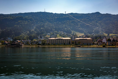 Scenic view of river by houses and mountains against sky