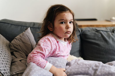 Portrait of cute girl sitting on sofa at home