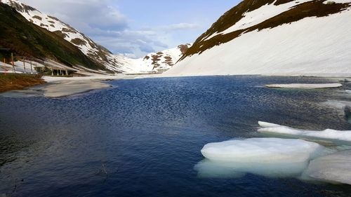 Snow covered mountain by lake against sky