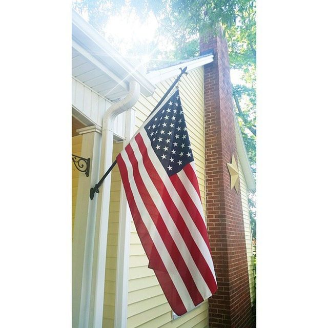 patriotism, american flag, national flag, flag, identity, low angle view, architecture, striped, built structure, building exterior, red, culture, transfer print, pride, day, no people, white color, auto post production filter, sky, modern