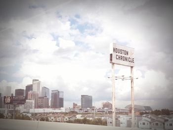 Information sign by buildings in city against sky