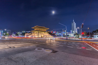 Light trails on road against buildings at night