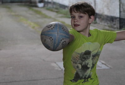 Portrait of boy wearing green t-shirt while playing outdoors