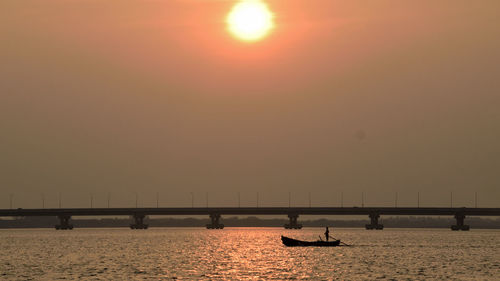 Scenic view of sea and bridge against sky at sunset