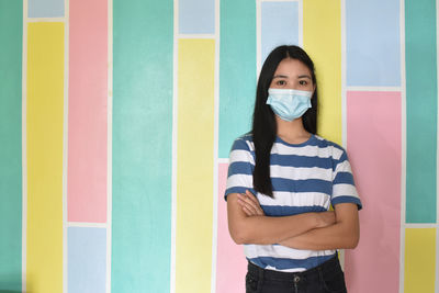 Portrait of young woman standing against multi colored wall